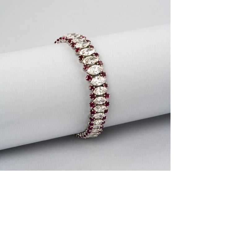 A Mid-20th century platinum, diamond and ruby bracelet. The slightly graduated flexible bracelet has a row of 44 marquise-cut diamonds with an approximate total weight of 13.40 carats, G/H color, VS clarity, accented by two outer rows of round-cut