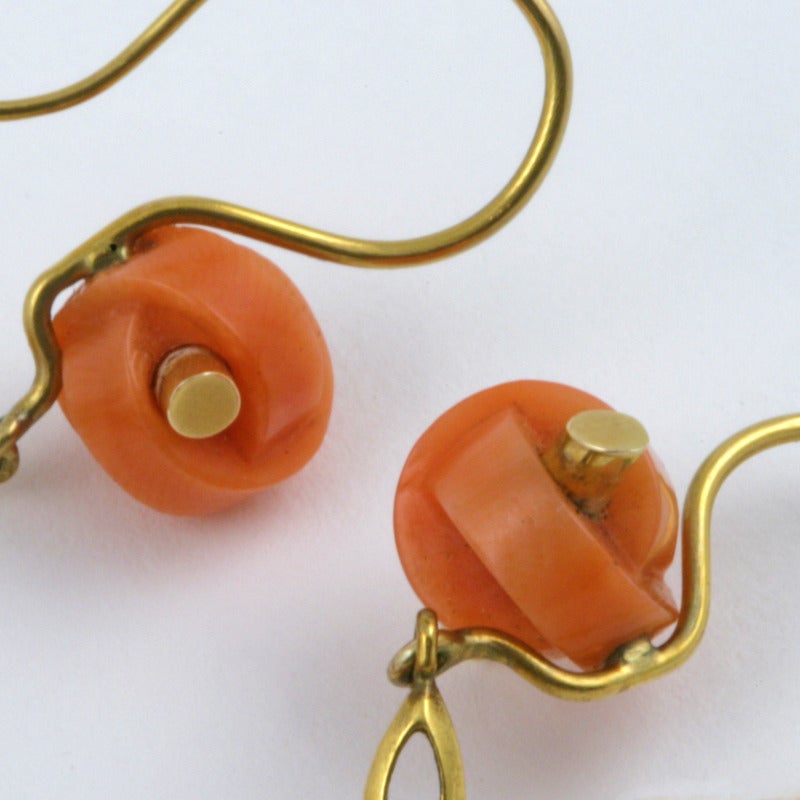 A pair of Antique 18 karat gold earrings with coral. The earrings have 2 carved coral tops and 6 tear drop-shaped corals.  The girandole coral earrings have gold foliate centers which are completely articulated and hang from the carved tops. Circa