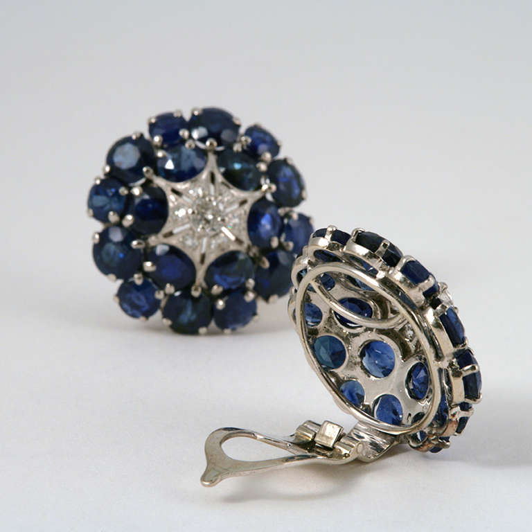 A pair of Mid-20th Century platinum, sapphire and diamond earrings. The circular earrings have an outside frame of 36 round blue sapphires with an approximate total weight of 12.60 carats. The center of the earrings have 14 diamonds with an