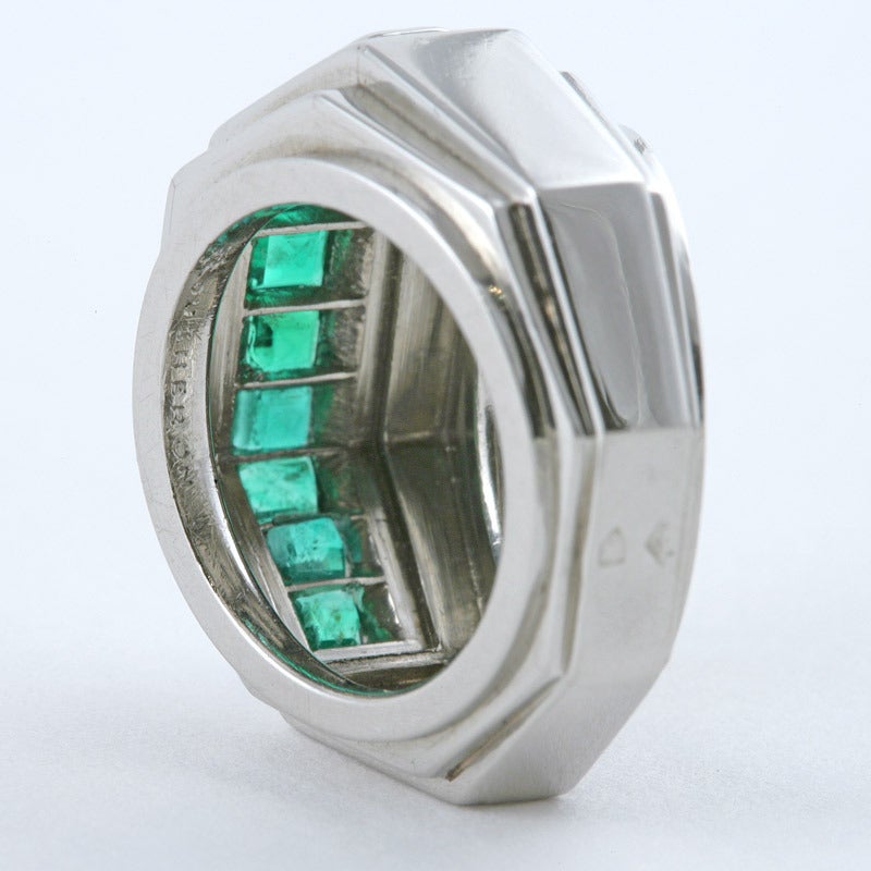 A French Art Deco emerald and platinum ring by Boucheron. The ring has 10 square-cut emeralds with an approximate total weight of 1.60 carats, channel set across the center of the stepped, octagonal shaped ring.  French control marks.  Circa 1930s.