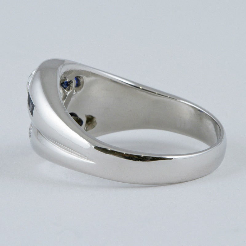Ein amerikanischer Art-Déco-Ring aus Platin mit Diamanten und Saphiren. Der Ring hat in der Mitte einen Diamanten im alten europäischen Schliff mit einem ungefähren Gewicht von 0,50 Karat, flankiert von 4 Saphiren im Kaliberschliff, und einen Saphir