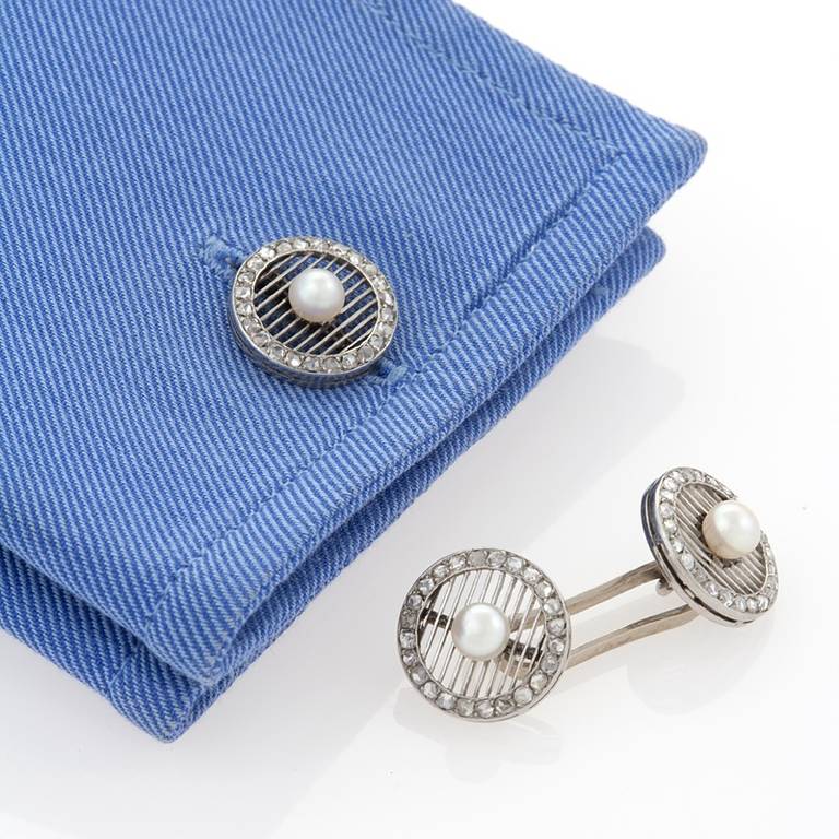 A pair of Portuguese Art Deco platinum cuff links with diamonds and cultured pearls. The circular cuff links have 96 rose-cut diamonds with an approximate total weight of .96 carat that surround the perimeter edge. Each side has an interior open