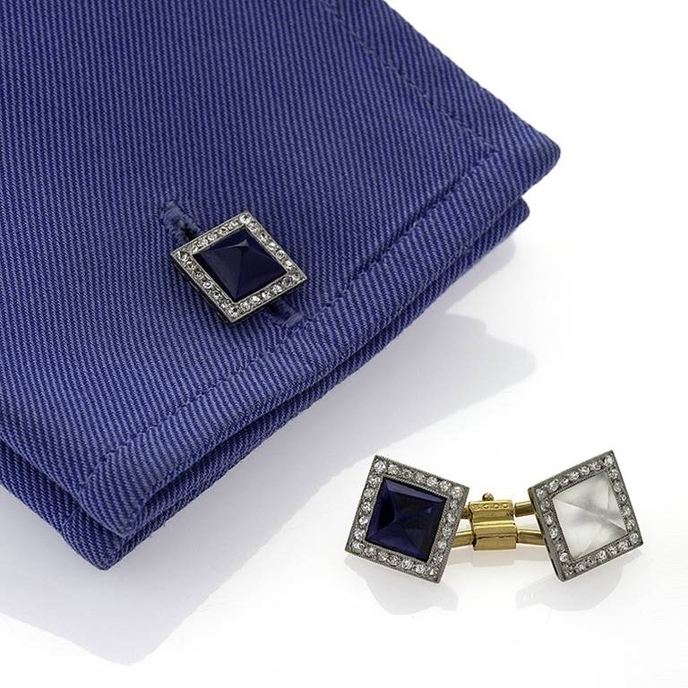 A pair of French Art Deco platinum, 18 karat gold, diamond and sapphire cuff links. The cuff links have pyramid cabochon sapphires and pyramid cabochon rock crystal that are surrounded by a square of old European-cut milligrain set diamonds. Circa