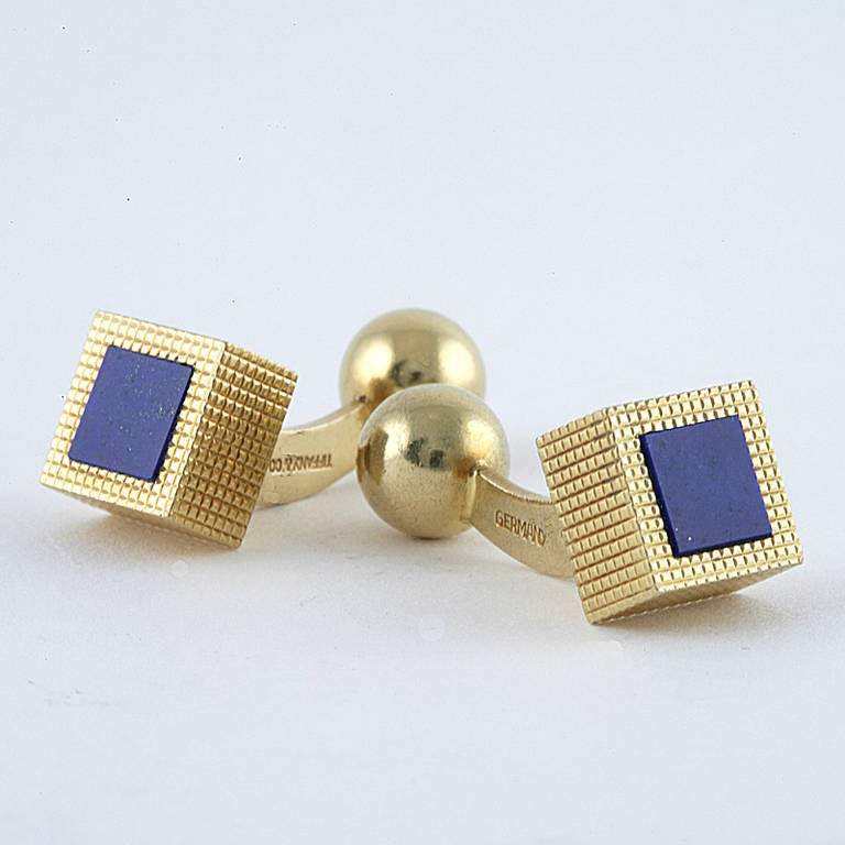 A pair of German-made Estate 18 karat gold cufflinks with lapis lazuli by Tiffany & Co. The three dimensional cube cufflinks have inlaid lapis lazuli stones atop the deeply grid carved cubes. With original signed Tiffany box. 

Circa 1980â??s.