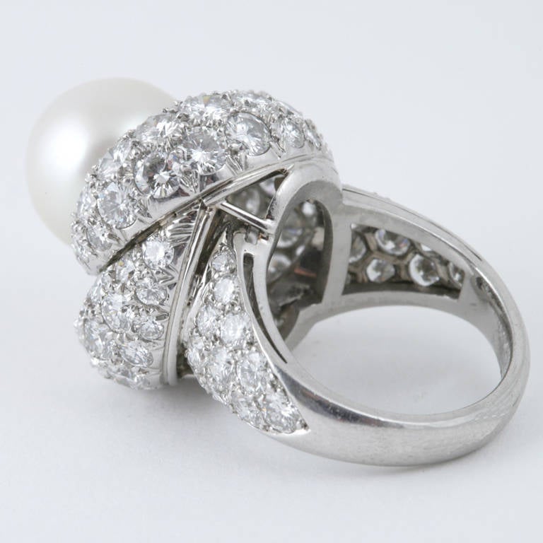 A Mid-20th Century platinum ring with diamonds and South Sea pearl. The ring is pavé set with diamonds with an approximate total weight of 9.50 carats, and a South Sea pearl measuring approximately 12.30 mm. The ring is designed in a swirl motif