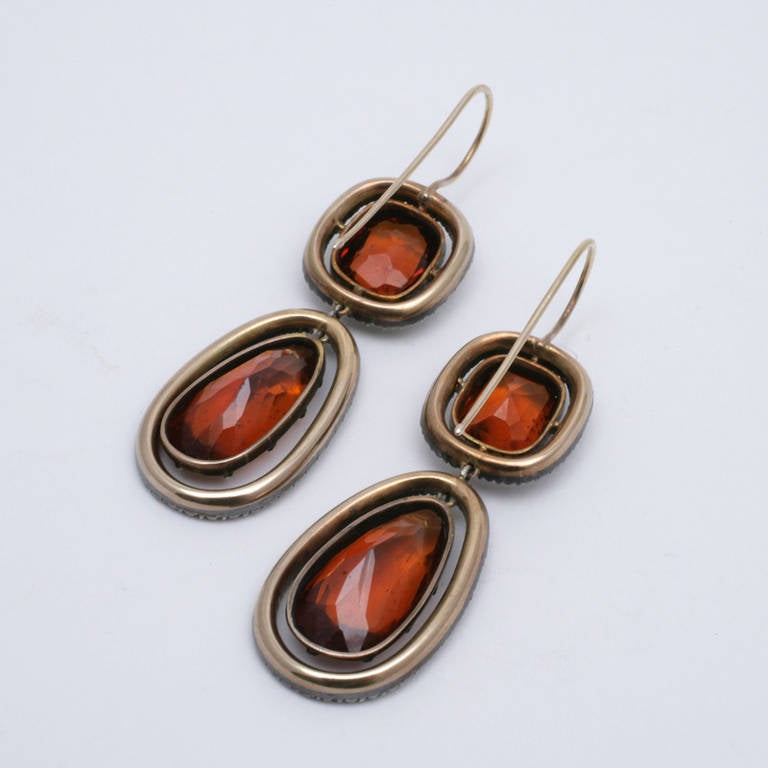 A pair of Antique 18 karat gold/silver top earrings with Hessonite garnet and diamonds. The earrings have 2 pear-cut garnets with an approximate total weight of 8.40 carats, 2 cushion-cut garnets with an approximate total weight of 4.40 carats, and