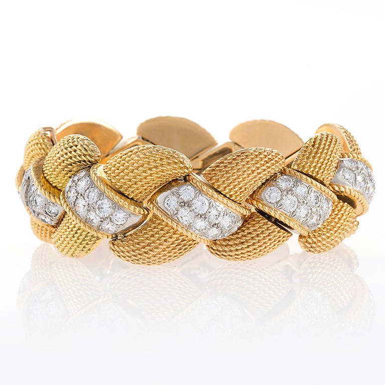 A Mid-20th Century 18-karat gold and platinum bracelet with diamonds by Van Cleef & Arpels. The bracelet features 92 round cut diamonds with an approximate total weight of 12.50 carats set with filigree gold in an overlapping rope motif. Circa 1959.