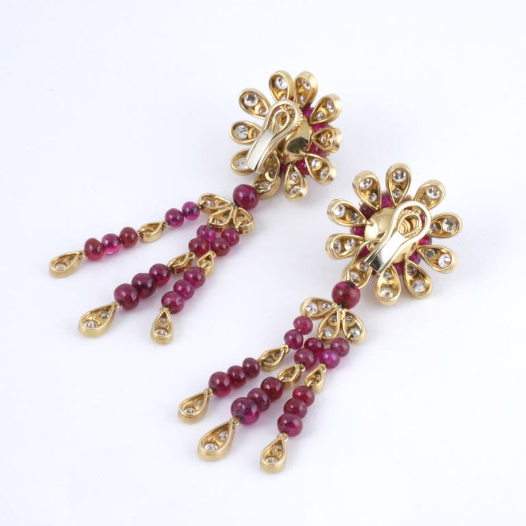 A pair of 18 karat gold earrings with diamonds and rubies. The earrings have 110 round-cut diamonds with an approximate total weight of 6.70 carats, and  66 beads rubies.  The earrings convert to ear clips when the drops are detached. Circa 1950’s.