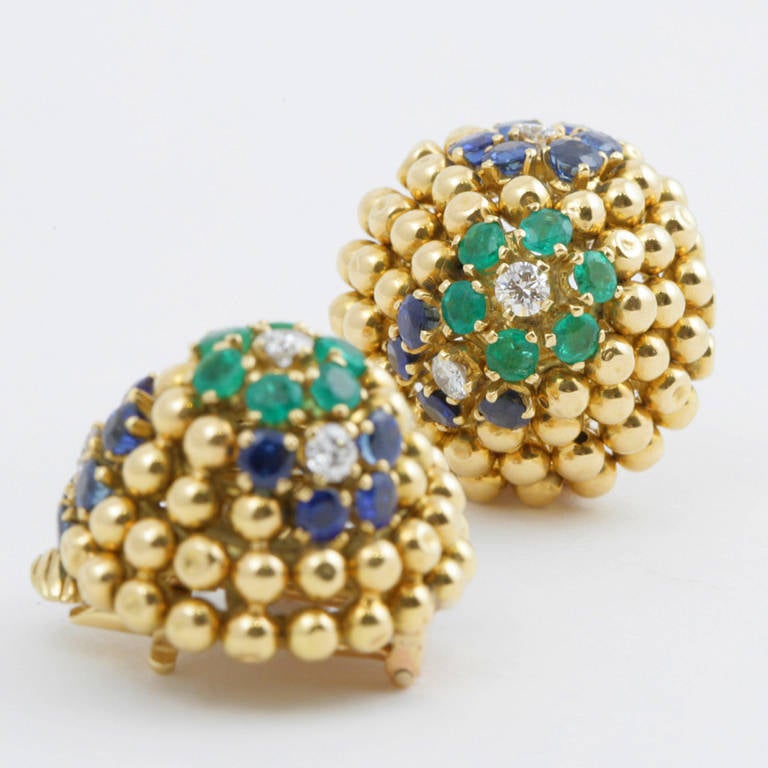 A pair of French Mid-Century 18 karat gold earrings with diamonds, sapphires and emeralds by Van Cleef & Arpels. The earrings have 6 round-cut diamonds with an approximate total weight of .52 carats, 20 round-cut sapphires with an approximate total