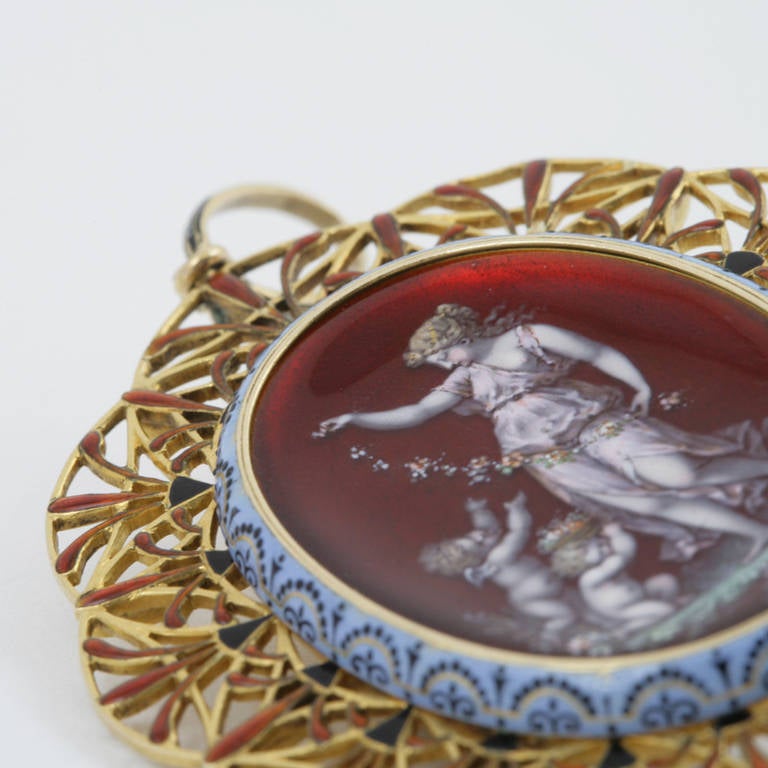 An Italian Etruscan Revival 18 karat gold pendant by Carlo Giuliano. The pendant centers on an enamel oval panel depicting a neoclassical woman and two putti, surrounded by an enamel openwork scalloped frame, richly enameled in periwinkle and deep