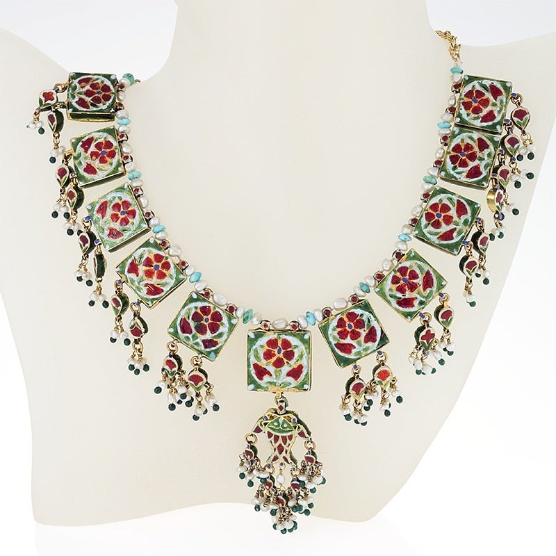 An Indian Mid 20th Century 18 karat gold and enamel necklace with turquoise, seed pearls and beads. The necklace has cabochon turquoise and pearl forming the floral designs of the 11 plaques with hanging turquoise set, pearl, bead and enamel fringe.