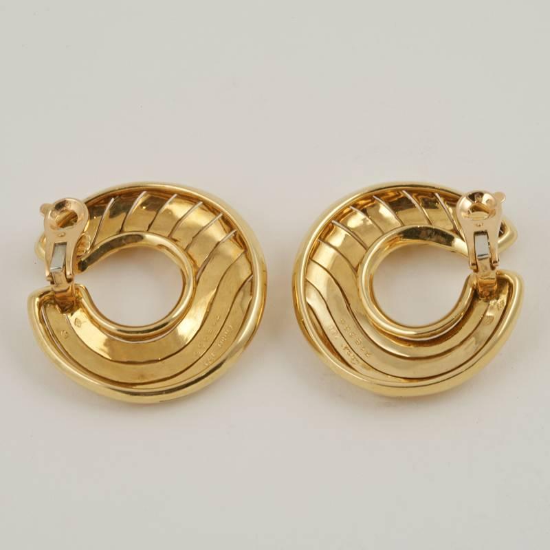 A pair of French Late-20th Century 18 karat gold earrings by Cartier Paris. The circular hoop earrings are uniquely ‘cut’ through the gold in a wave motif.  Circa 1980's. 

Signed, “Cartier 718966 750” French control mark. 

(MG #17092)