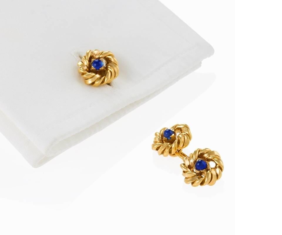 A pair of French Mid-20th Century 18 karat gold cuff links with sapphires by Van Cleef & Arpels. The cuff links have 4 cabochon sapphires with an approximate total weight of .40 carats. The box mounted sapphires are surrounded by heavy twisted gold
