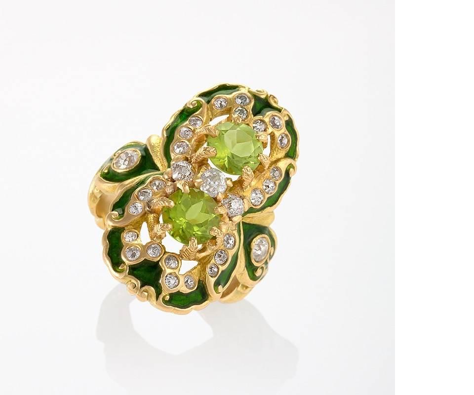 An American Art Nouveau gold, peridot, diamond and enamel ring by Marcus & Co. The unique Renaissance Revival motif features green enameled 18-karat gold, two round-cut peridots totaling approximately 1.60 carats, and 30 round-cut diamonds that