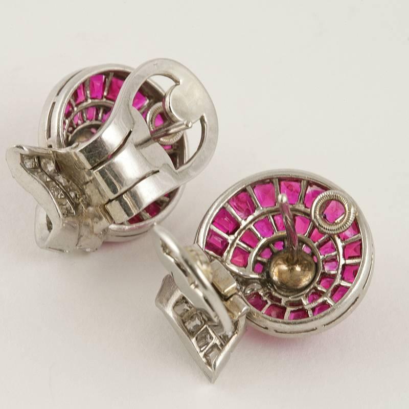 A pair of Retro platinum earrings with rubies and diamonds. The earrings have 64 calibre-cut rubies with an approximate total weight of 3.10 carats, 2 round-cut diamonds with an approximate total weight of .50 carats, and 34 baguette and round-cut