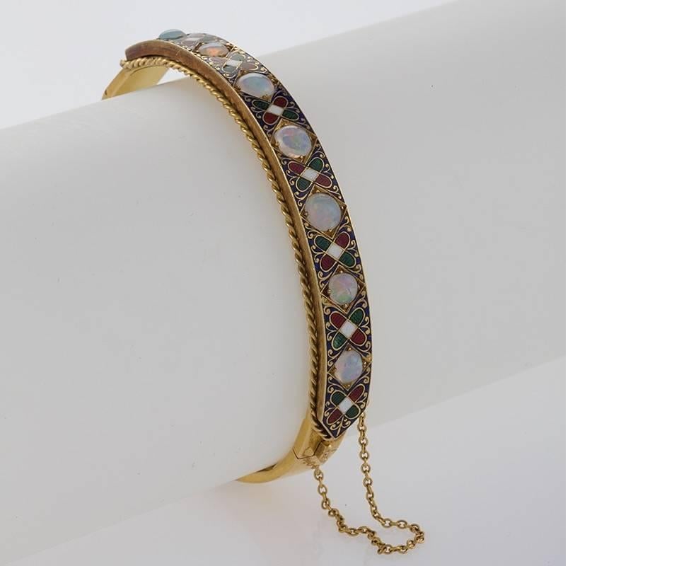 An English Victorian 18 karat gold and enamel bracelet with white opals. The bracelet contains 7 white opals alternating with Holbeinesque enamels.  The bangle is enhanced with rope gold detail. Circa 1880. 

Holbeinesque-style jewelry is jewelry