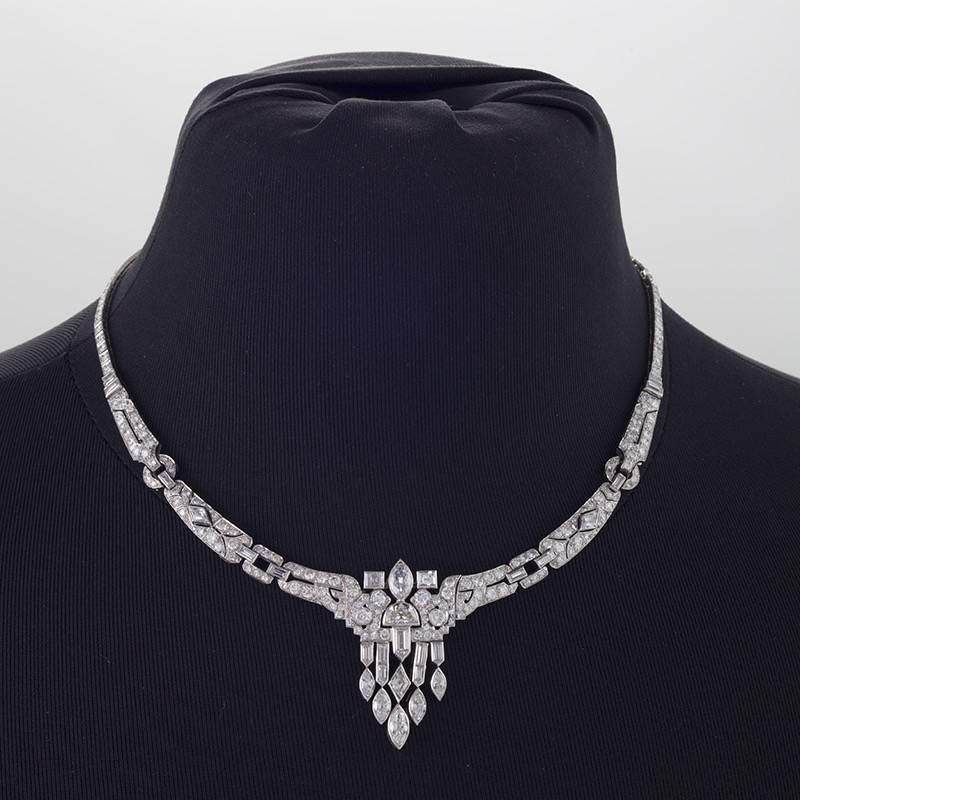 Created in the late Art Deco period, this finely articulated, platinum pierce-work collar necklace is set with over seventeen carats of round and fancy-cut diamonds. The subtly-tapering form centers flexible tassels accented by half-moon-,
