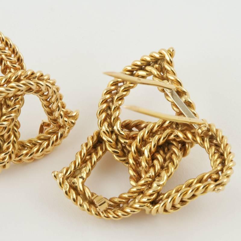 A pair of French Mid-20th Century 18 karat gold brooches by Sterlé Paris. The brooches are composed of woven braided gold in a modified Celtic knot motif. 
Circa 1950’s. 

Similar earrings pictured in Sterlé Joaillier Paris, by  Viviane