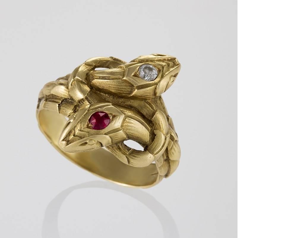 A French Antique 18 karat gold serpent ring with diamond and ruby. The ring has a round diamond with an approximate weight of .10 carats, and a round ruby with an approximate weight of .10 carats.  The double serpent entwined ring symbolizes a