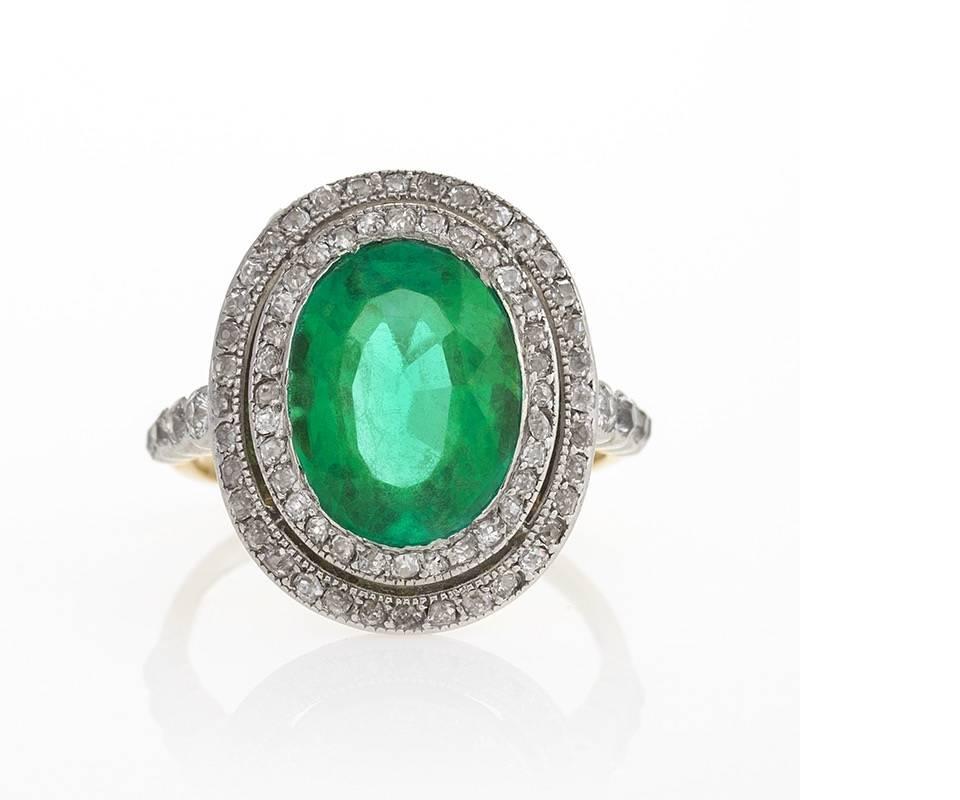 This antique Edwardian gold-shanked ring is set with a four-and-a-half carat oval-cut emerald, exhibiting the classic slightly bluish-green that signifies its rare and desirable Colombian origin. Encircled by a double line of fiery old mine-cut