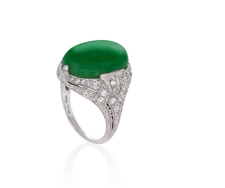 An American Art Deco platinum ring with jadeite and diamonds by Jung & Klitz. The ring has a cabochon jadeite measuring 15.90 x 11.35 x 4.28 mm, and old European-cut and bullet cut diamonds with an approximate total weight of 1.00 carats. Mason-Kay