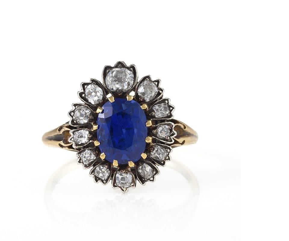 An Antique silver topped gold ring with sapphire and diamonds. The ring has a cushion-cut sapphire that weighs 3.03 carats, and 12 old mine-cut diamonds with an approximate total weight of .85 carats. The ring is in a classic cluster style with