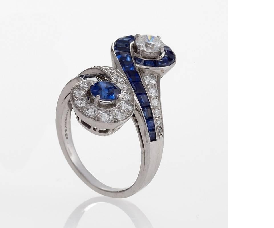 A Mid-20th Century platinum ring with sapphires and diamonds by Tiffany & Co. The Toi et Moi ring has a center round sapphire with an approximate total weight of .40 carats, and 23 calibre cut sapphires with an approximate total weight of .95
