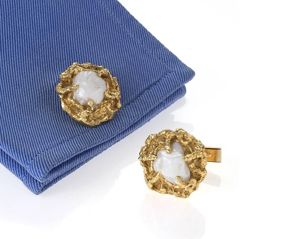 A pair of American Mid-20th Century 18 karat gold cuff links with Baroque pearls by Arthur King. The cuff links have 2 Baroque pearls measuring approximately 10 x 10 mm set in highly free form textured gold. 

Arthur King was a master goldsmith