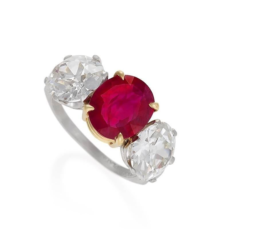 An 18 karat gold and platinum ring with ruby and diamonds. The ring centers on an oval mixed cut Burmese ruby with an approximate weight of 2.56 carats, and two Old European-cut diamonds with an approximate total weight of 5.00 carats,  H/I color,