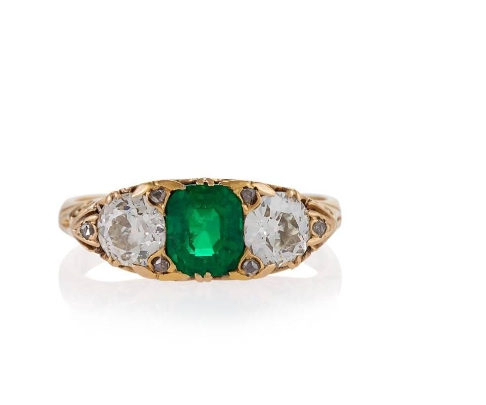 An English Antique 18 karat gold ring with emerald and diamonds. The classic three-stone ring has a cushion-cut emerald with an approximate total weight of 1.00 carats,, flanked by 2 old European-cut diamonds with an approximate total weight of 1.30
