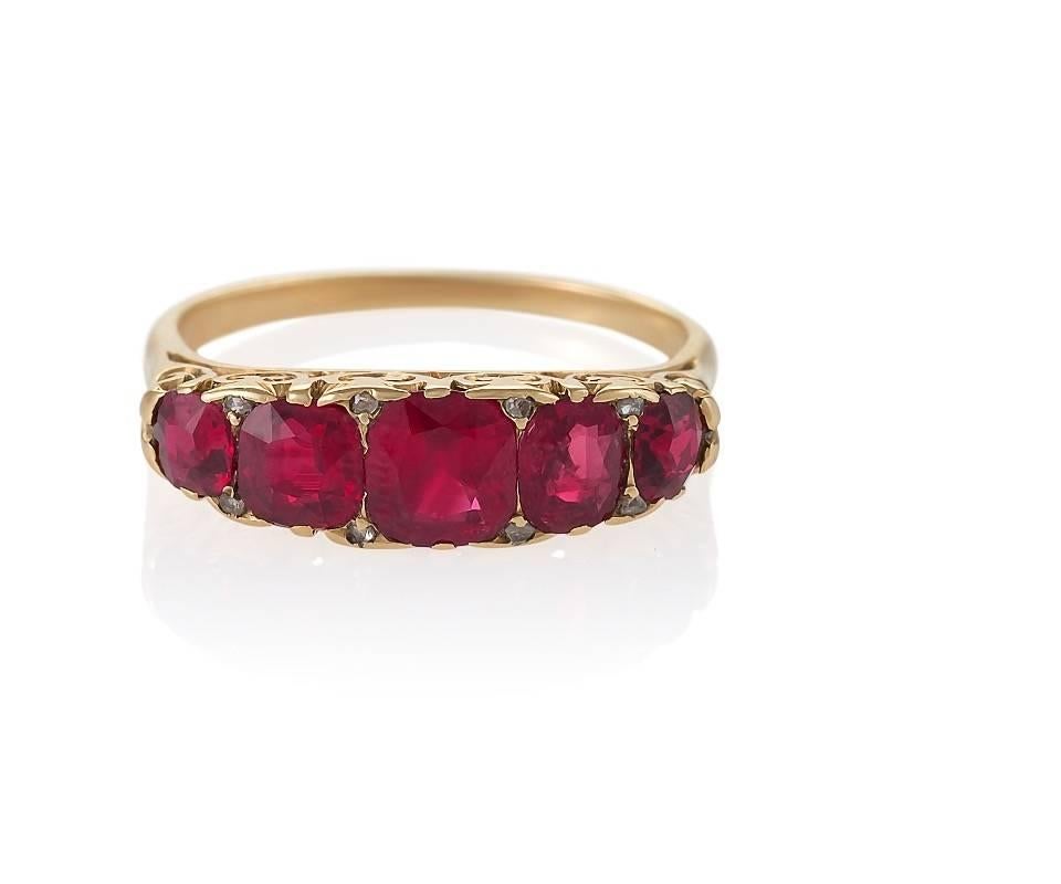 An English Antique 18 karat gold ring with ruby. The ring has 5 graduated cushion-cut rubies with an approximate total weight of 1.60 carats, and 8 rose cut diamonds with an approximate total weight of .08 carat.  The ring has cut out scroll work