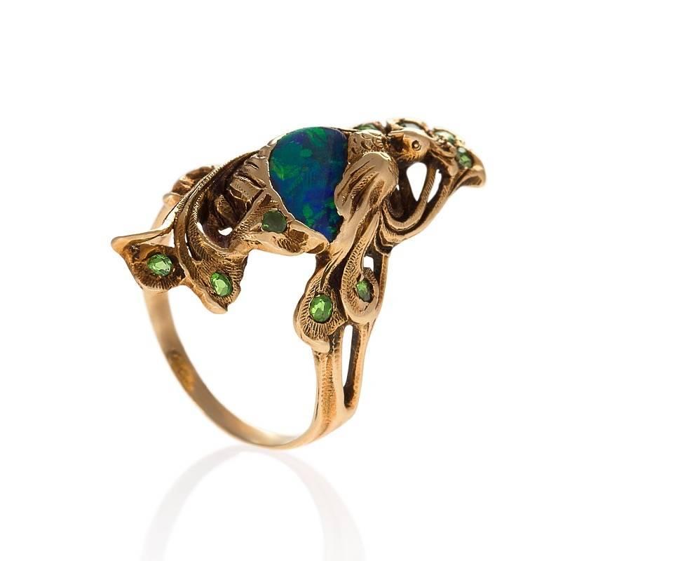 An Art Nouveau 14 karat gold ring with black opal and demantoid garnets by Walton & Co. The ring has a black opal, and 11 round-cut demantoid garmets with an approximate total weight of .22 carats.  The ring is in the form of a peacock with the