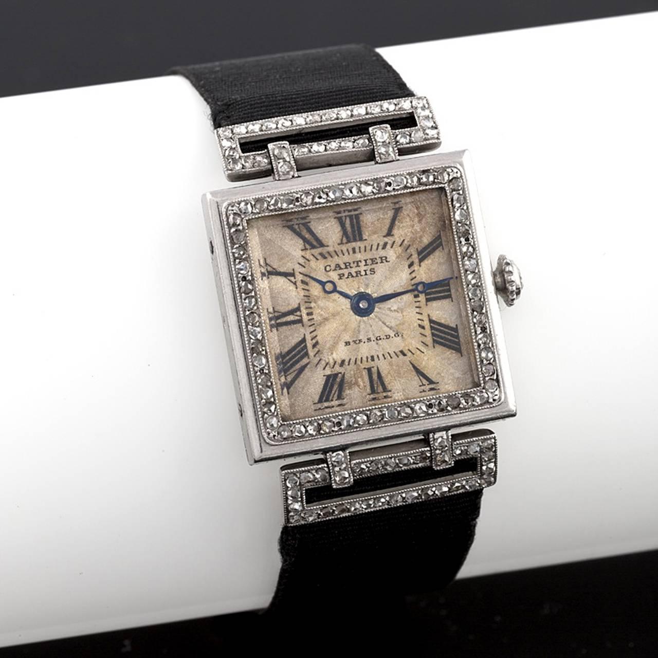 A Cartier Art Deco platinum and 18k gold 'Tank' watch with diamonds. The watch has 117 rose-cut diamonds. The deployant buckle is 18k gold set with diamonds on a silk strap. Dial:  7/8” square. Deployant strap adjustable. Circa 1920. 

Numbered 8165
