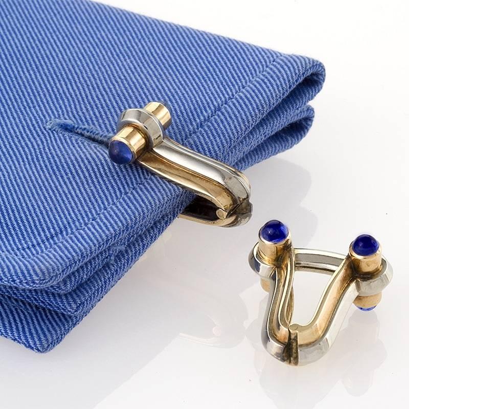 A pair of mid-20th Century 14 karat gold and platinum hinged stirrup cuff links with blue sapphires. The cuff inks feature 8 cabochon blue sapphires, 2 on each end, with an approximate total weight of 1.20 carats. Circa 1960's. 
(MG #13368)