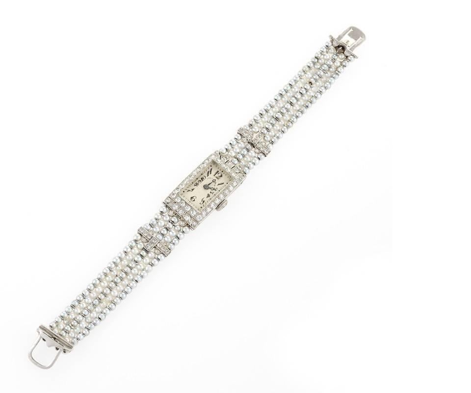 An American Art Deco platinum and white gold watch with diamonds and seed pearls by Dreicer & Co. The rectangular faced watch has 68 single-cut diamonds with an approximate total weight of .76 carats surrounding the platinum case and accenting