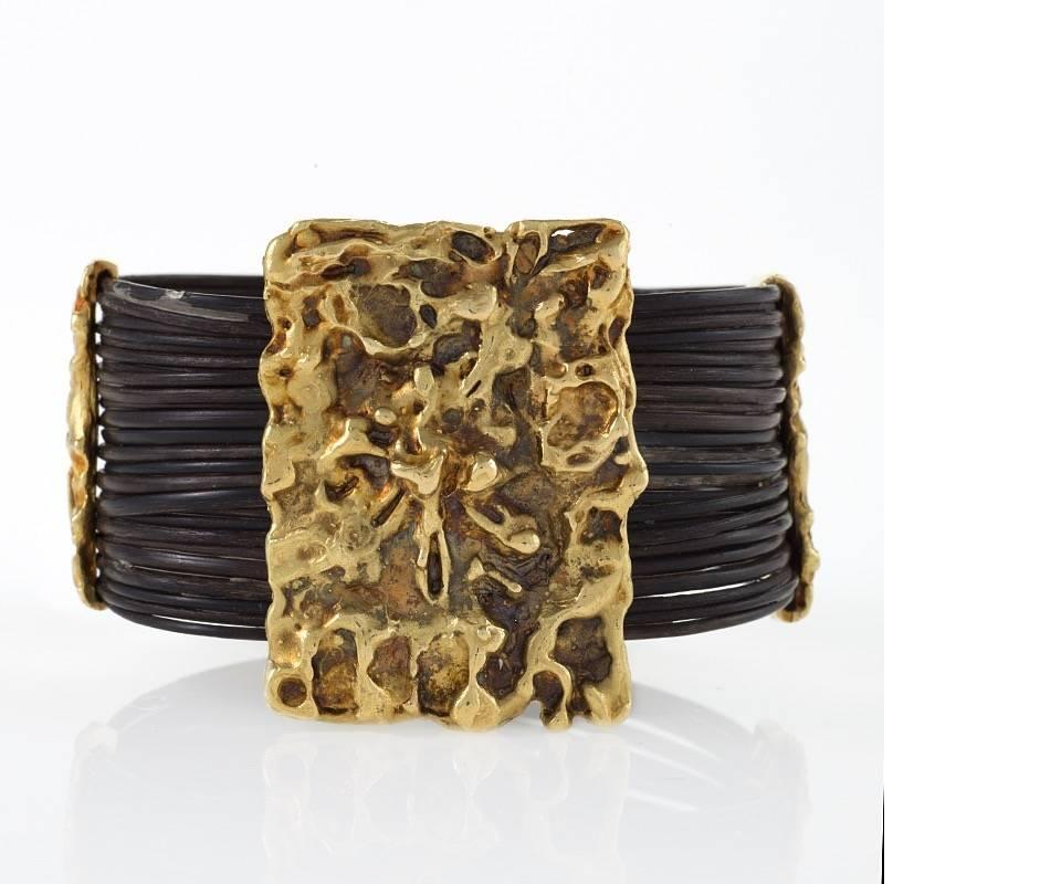 A French Mid-20th Century 18 karat gold and elephant hair bracelet by Van Cleef & Arpels. The bracelet has a central rectangular plaque with a highly textured Modernist motif. There are 3 similar textured spacers which hold the strands of elephant