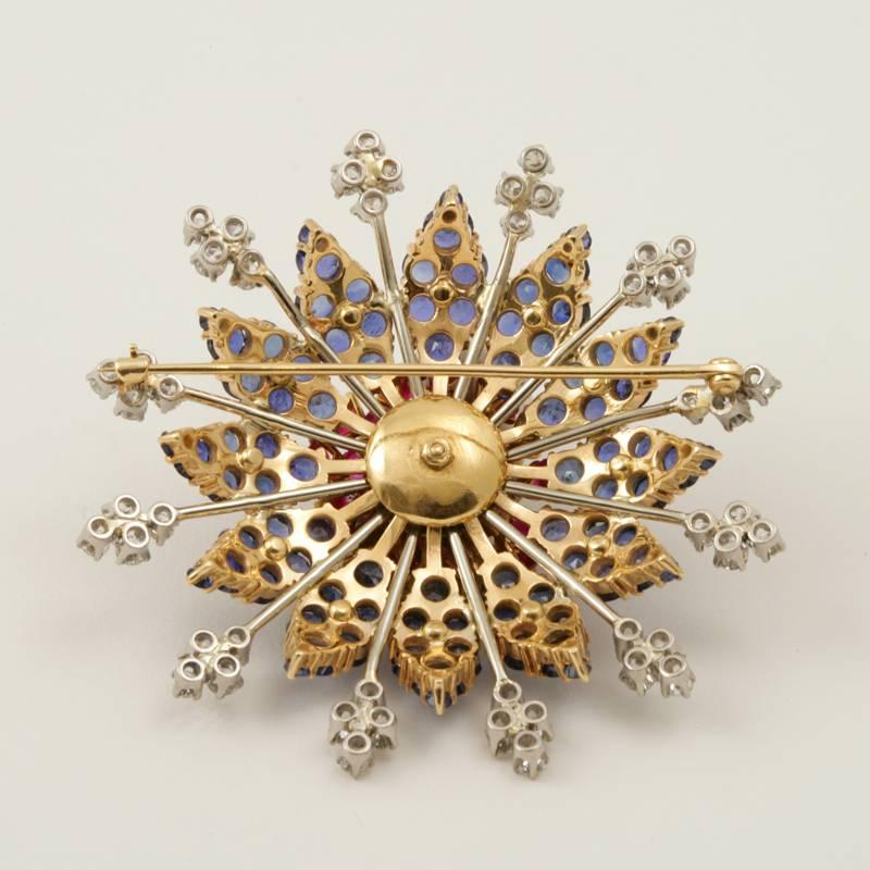 A Retro platinum and 14 kt gold brooch with rubies, diamonds and sapphires. The stylized and dimensional star brooch has 29 round-cut rubies with an approximate total weight of 6.75 carats, 64 round-cut diamonds with an approximate total weight of