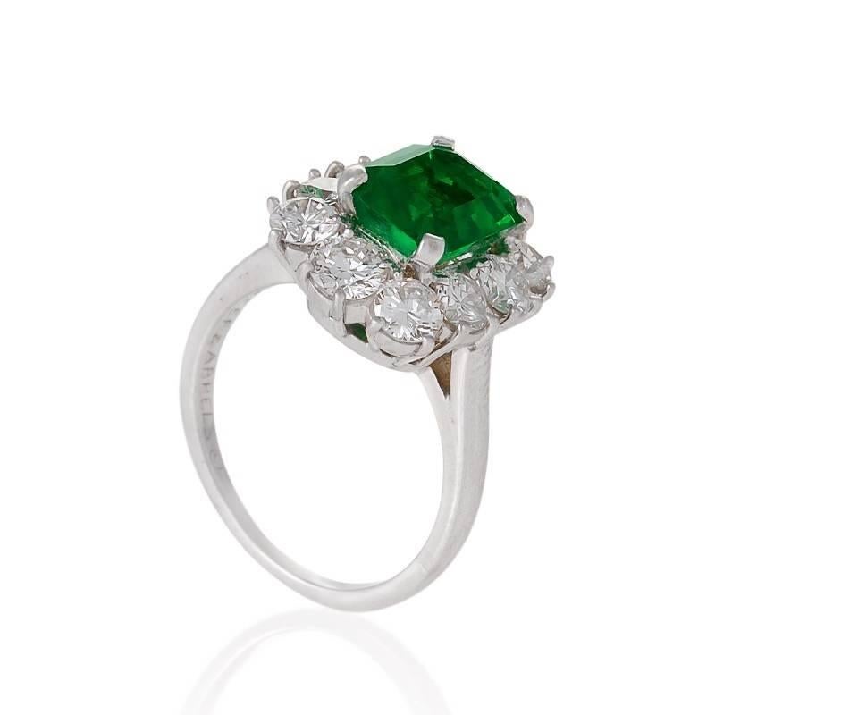 A Mid-20th Century platinum, emerald and diamond ring by Van Cleef & Arpels. The cluster ring centers on an octagonal step-cut emerald with an approximate weight of 1.80 carats.  Surrounding the emerald are 10 round brilliant-cut diamonds with an