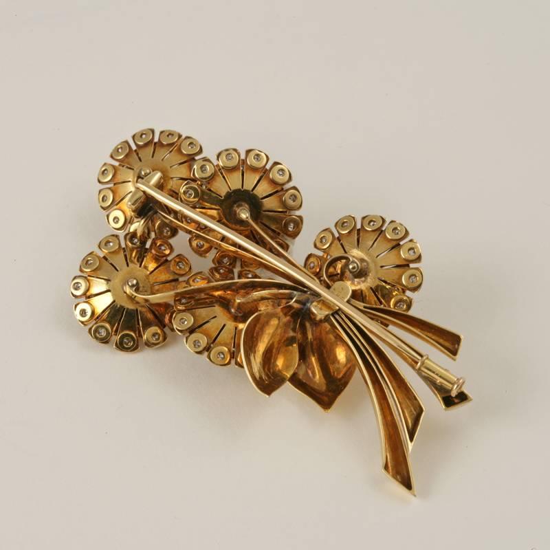 A French Retro 18 karat gold brooch with diamonds by Van Cleef & Arpels. The brooch has 125 round diamonds with an approximate total weight of 3.50 carats. The brooch is composed in a stylized Retro motif of a bouquet of flowers in polished gold. 