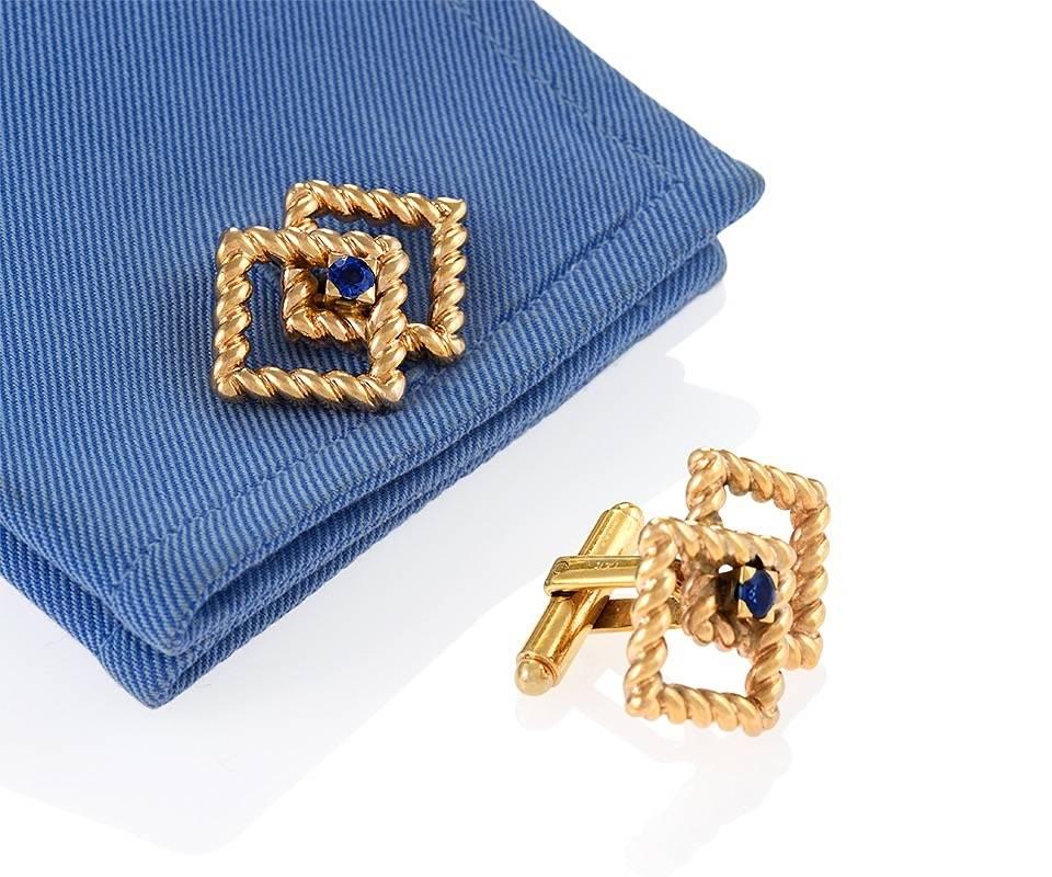 A pair of Mid-20th Century 14 karat gold cuff links with sapphires by Tiffany & Co. The cuff links have 2 round sapphires with an approximate total weight of .35 carats. The box set sapphires are centered in two overlapping rope gold rhomboids. 