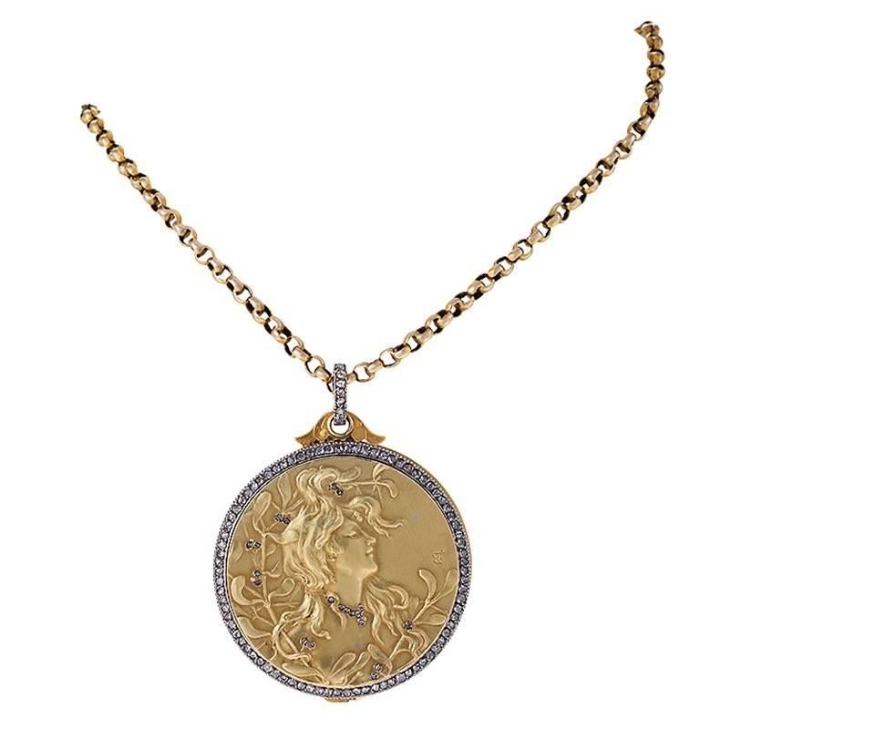 A French Art Nouveau 18 karat gold and platinum pendant locket with diamonds. This repoussé slide locket depicts a profile of a woman that is surrounded by a frame of 96 rose-cut diamonds with an approximate total weight of .96 carats. The locket