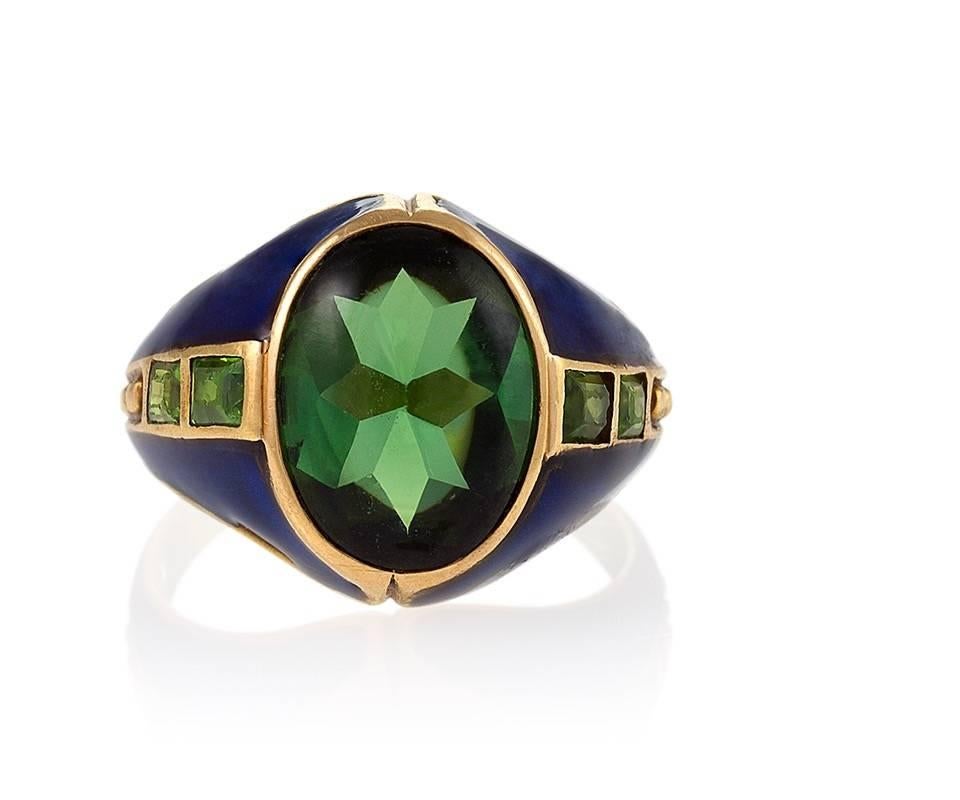 An American Art Nouveau 18 karat gold and enamel ring with peridots by Tiffany & Co. The ring centers on a double-cut, cabochon and faceted peridot with an approximate total weight of 4.25 carats., and 4 calibre-cut peridots,  The calibre peridots