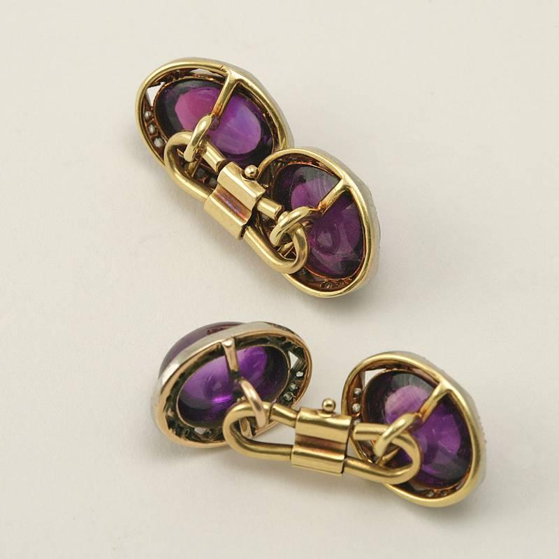 A pair of English Edwardian platinum and 15 karat gold cuff links with amethysts and diamonds. The cuff links have two cabochon amethysts with an approximate total weight of 19.60 carats, and 72 rose-cut diamonds with an approximate total weight of