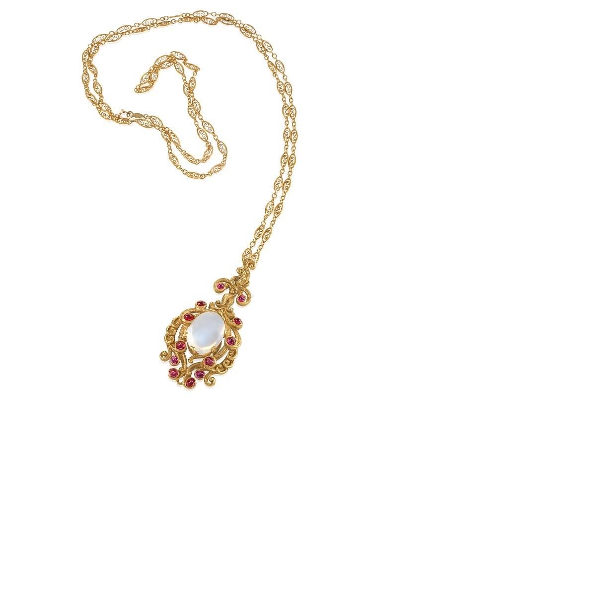 An American late-19th Century 14 karat gold pendant with moonstone and rubies. The pendant has a cabochon moonstone with an approximate total weight of 14.30 carats, and 12 cabochon rubies with an approximate total weight of 1.20 carats. With 14