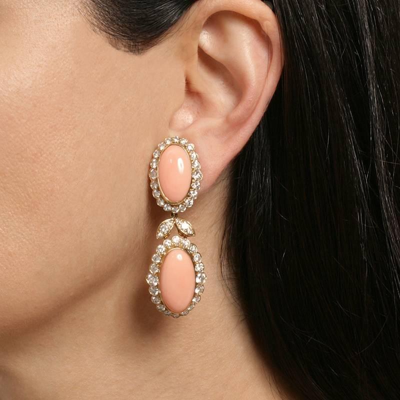 These charming coral and diamond drop earrings by Van Cleef & Arpels are a delightful confection. Decadent oval coral cabochons framed by round-cut diamonds are embellished with a darling ribbon motif, recalling the French court’s gilded romance,