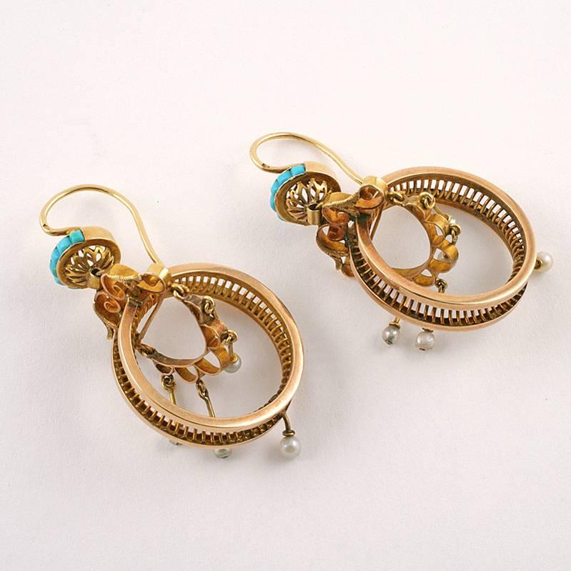 A pair of French Antique 18 karat gold ear pendants with turquoise and seed pearls. The earrings have 12 calibre cut turquoise stones, and 10  seed pearls. The earrings are composed of a wheel suspended from a scrolled gold yoke, topped with a disk