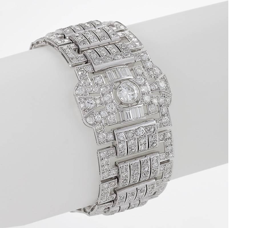 Dating from the 1930s, this striking and finely-articulated French Art Deco bracelet features approximately twenty-eight carats of diamonds set in platinum. Composed of three openwork plaques alternating with groups of open rectangular links joined