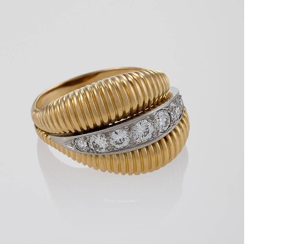 A French Mid-20th Century 18 karat gold and platinum ring with diamonds by Van Cleef & Arpels. The ring has 7 round-cut diamonds with an approximate total weight of .70 carat, G/H color, VS clarity grade. The central diamond set platinum line is