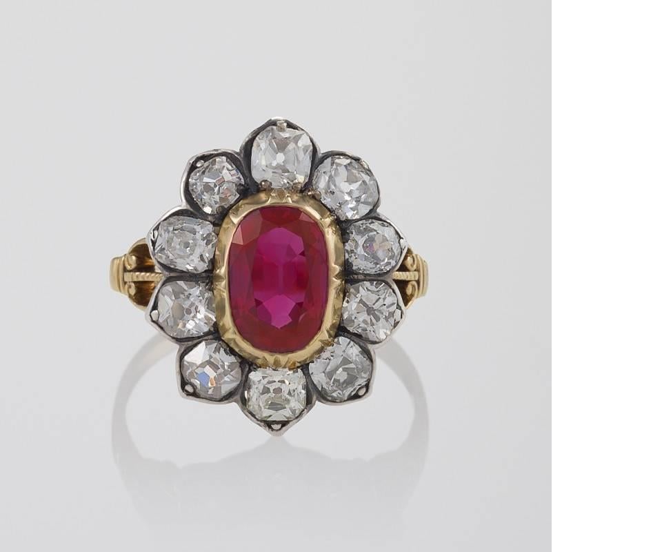 An Antique English 18 kt gold and oxidized silver ring with ruby and diamonds. The ring has an oval ruby with an approximate weight of 2.13 carats, and 10 old mine cut diamonds with an approximate total weight of 2.00 carats.  The ring is composed