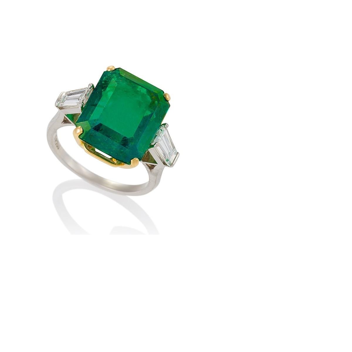 This large and precious nearly nine-carat Colombian emerald estate ring exhibits a classic, slightly bluish-green hue, thanks to the presence of rare trace elements. A timeless design that centers the emerald-cut stone flanked with tapering diamond